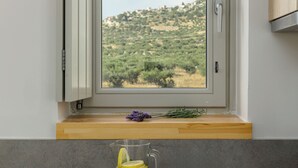 Una cocina con ventana que da a un paisaje montañoso, encimera de madera y tres vasos con rodajas de limón.