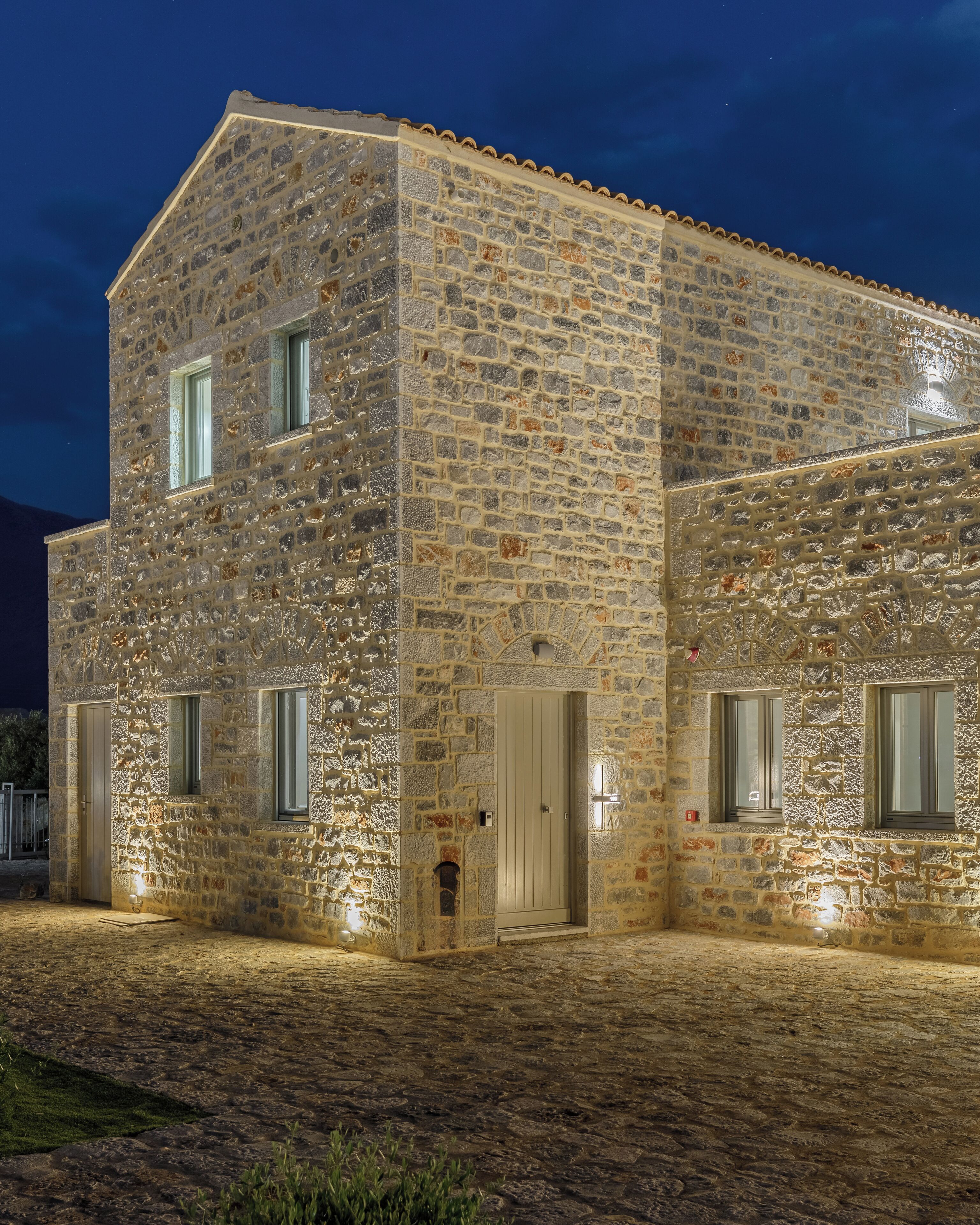 Un edificio de piedra con techo plano, una puerta y ventanas.