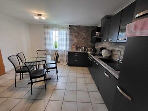 Una cocina compacta con una mesa y sillas, un refrigerador y un salpicadero de piedra.