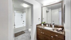 Et moderne badeværelse med et stort spejl, vask og bruseområde.
