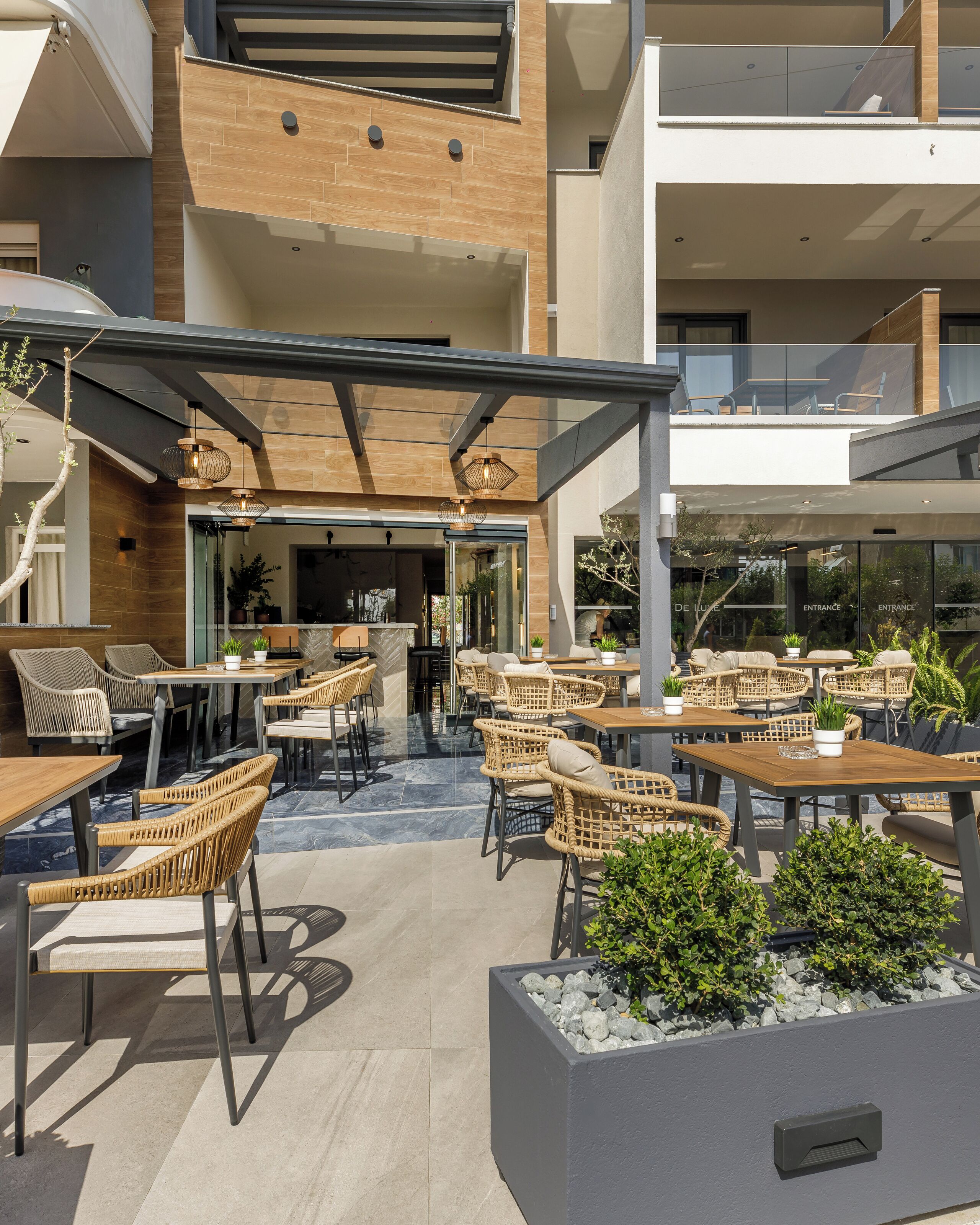 Un patio al aire libre con mobiliario de mimbre y una entrada de vidrio al edificio.