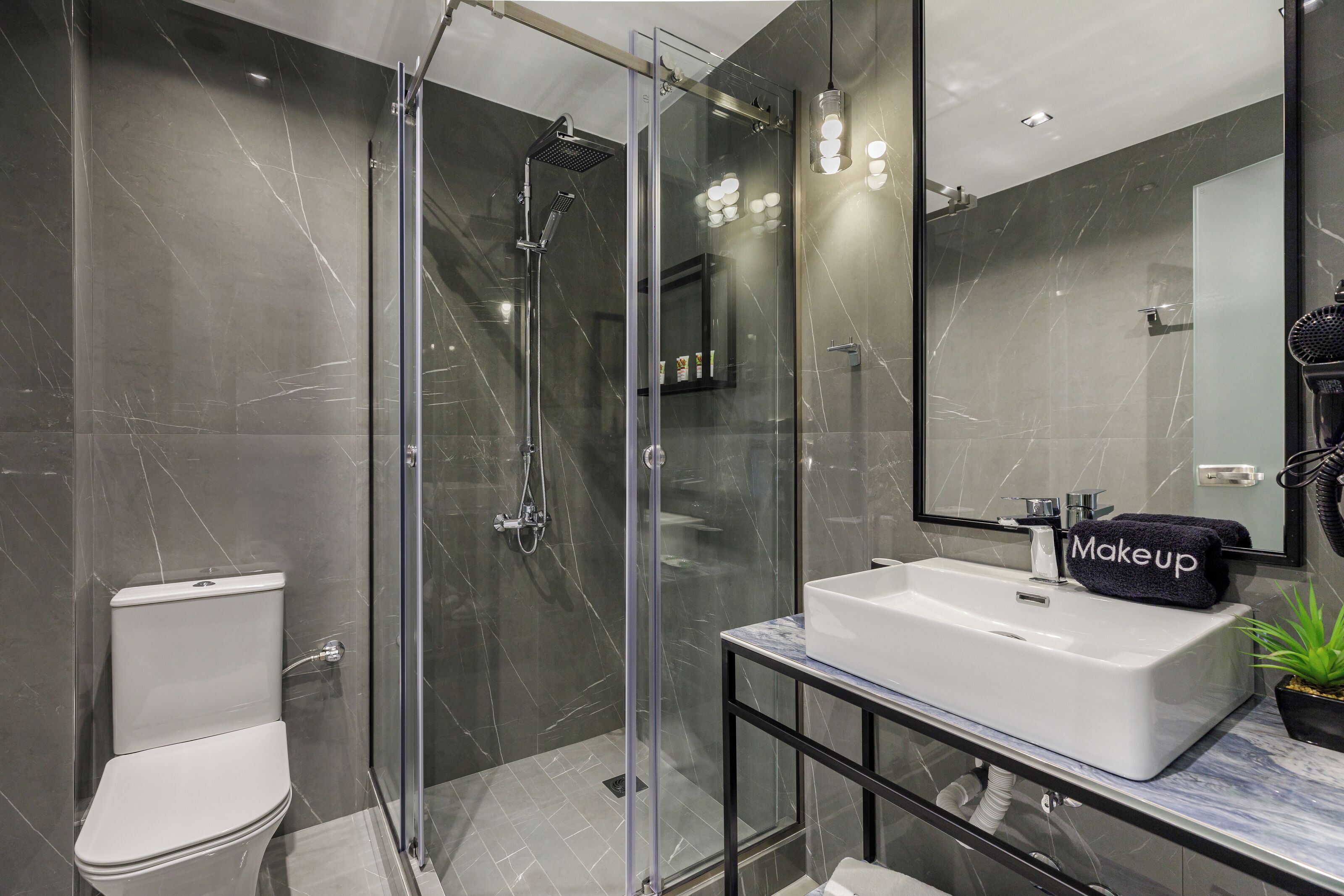 A modern bathroom with a glass-enclosed shower, a white sink, and a vanity with a mirror.