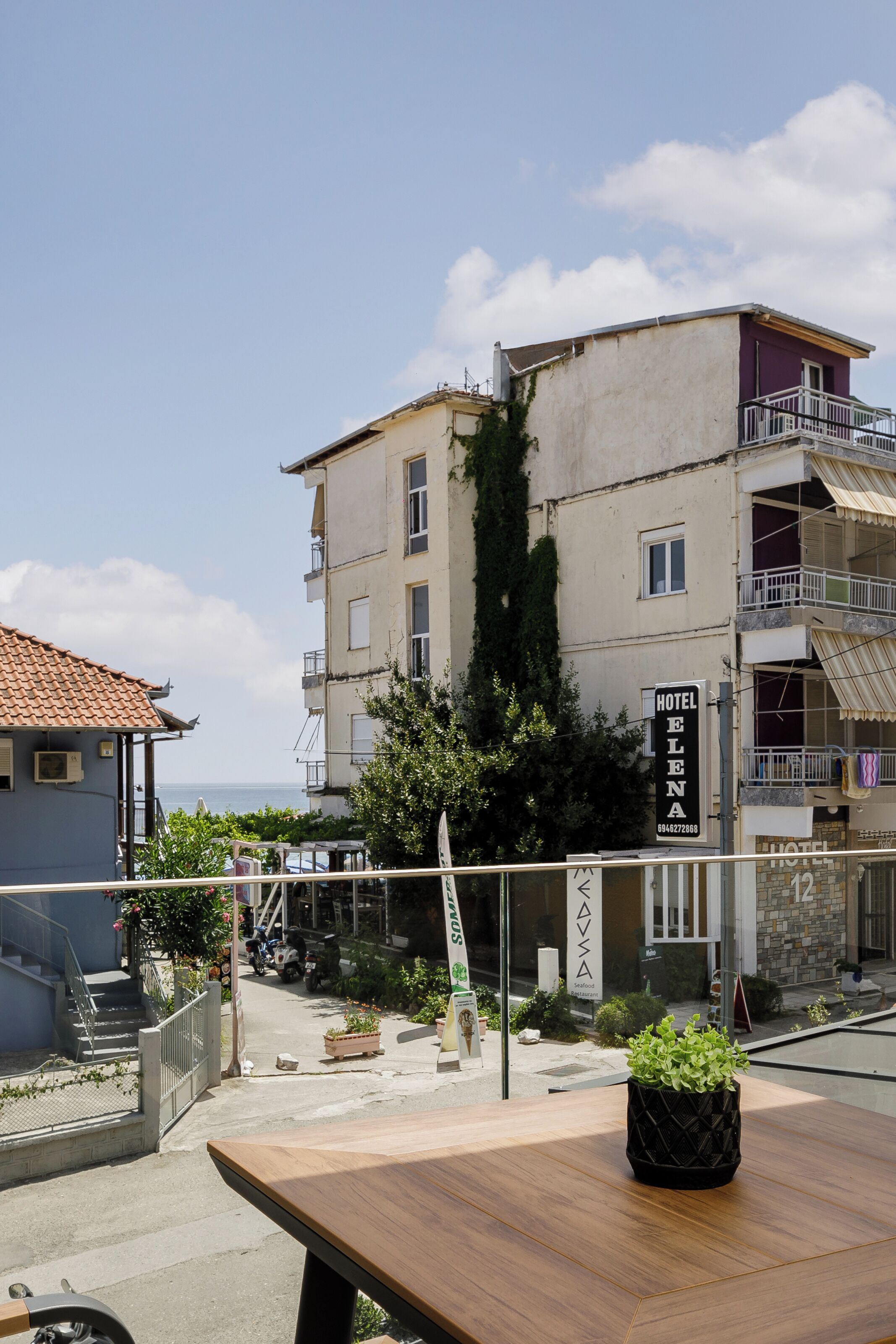 A hotel named "Hotel Elena" with a signboard, a balcony, and a view of the sea.