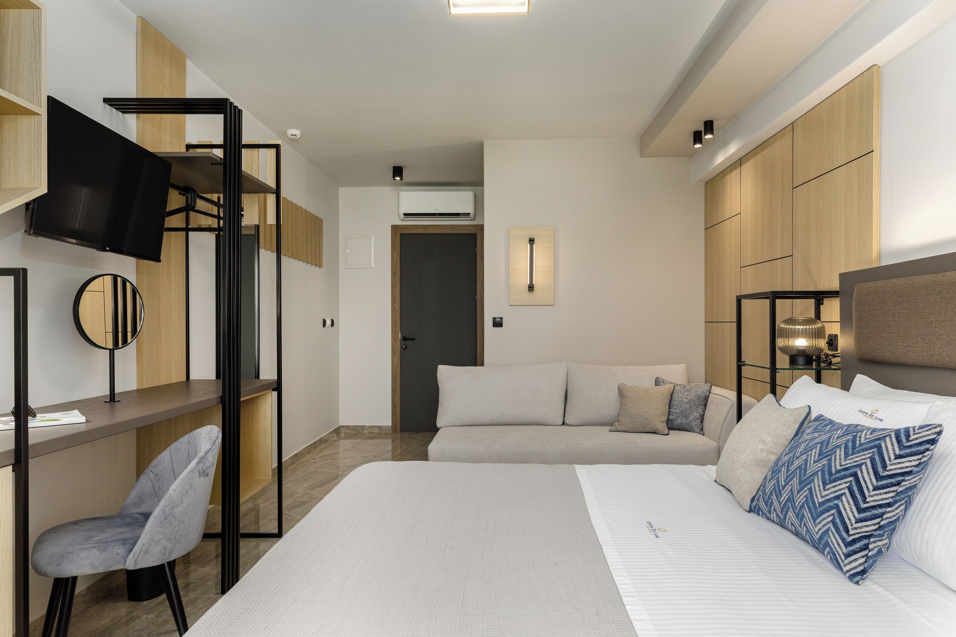 Una habitación de hotel moderna con una cama, un escritorio, una silla, un televisor y armarios empotrados de madera.