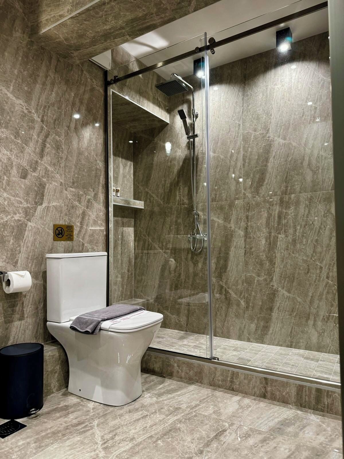 Un bagno moderno con doccia vetrata, un water e una parete in marmo.