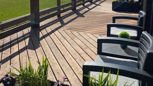 Eine Holzterrasse mit Geländer, Gartenmöbeln und Blumentöpfen.