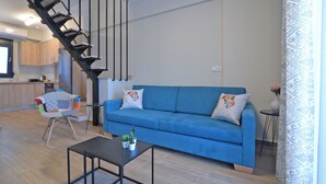 Ein modernes Wohnzimmer mit einem blauen Sofa, einem schwarzen Couchtisch und einer Treppe.