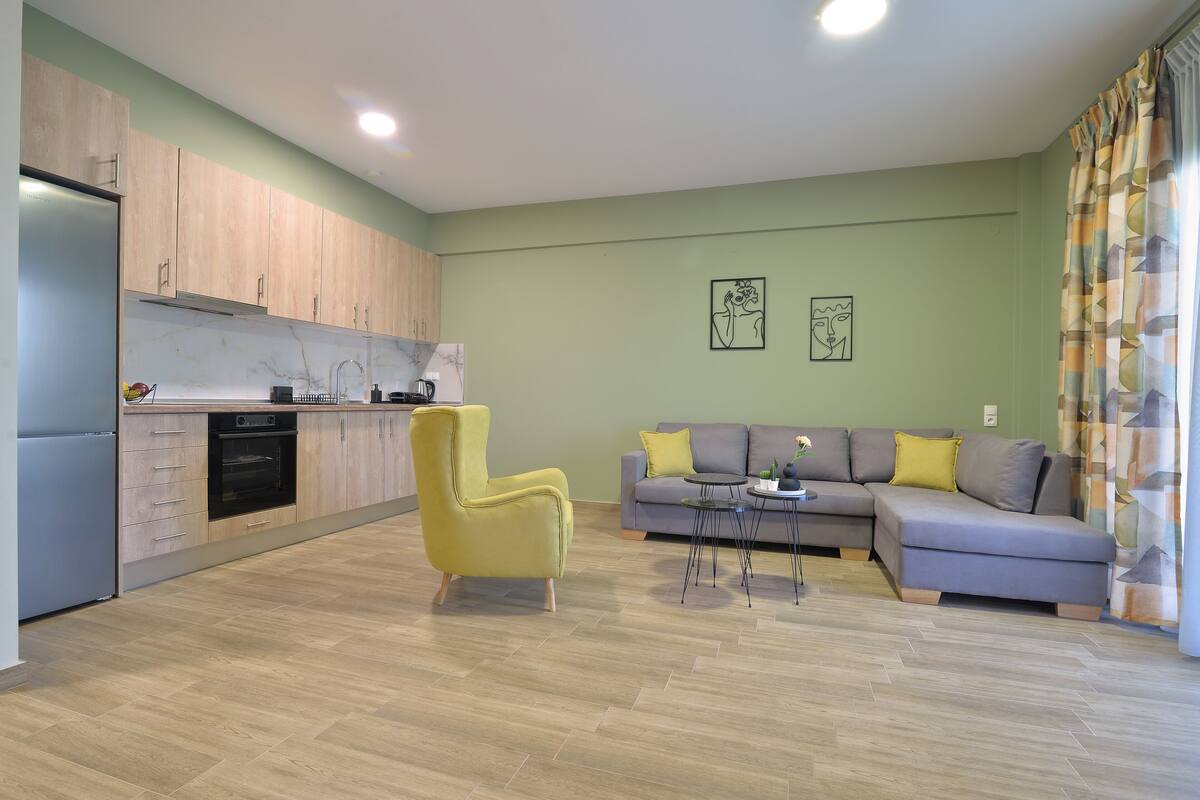 Una sala de estar moderna con un sofá, un sillón amarillo y una pequeña mesa.