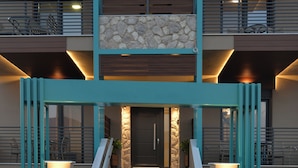 Ein mehrstöckiges Wohngebäude mit einer zentralen Treppe, einer Stein-Fassade und türkis-farbenen Geländern.