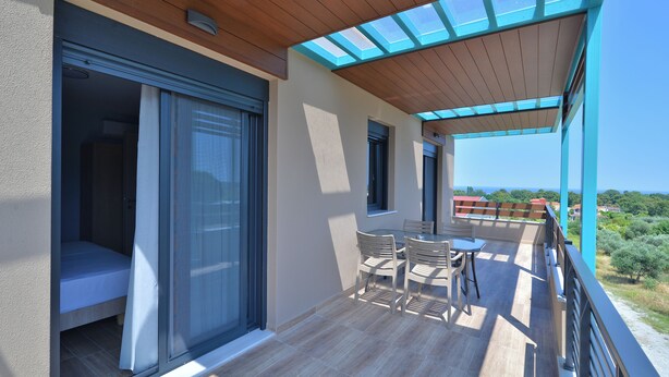 Ein Balkon mit Holzboden, einer Glastür und einem Tisch mit Stühlen.