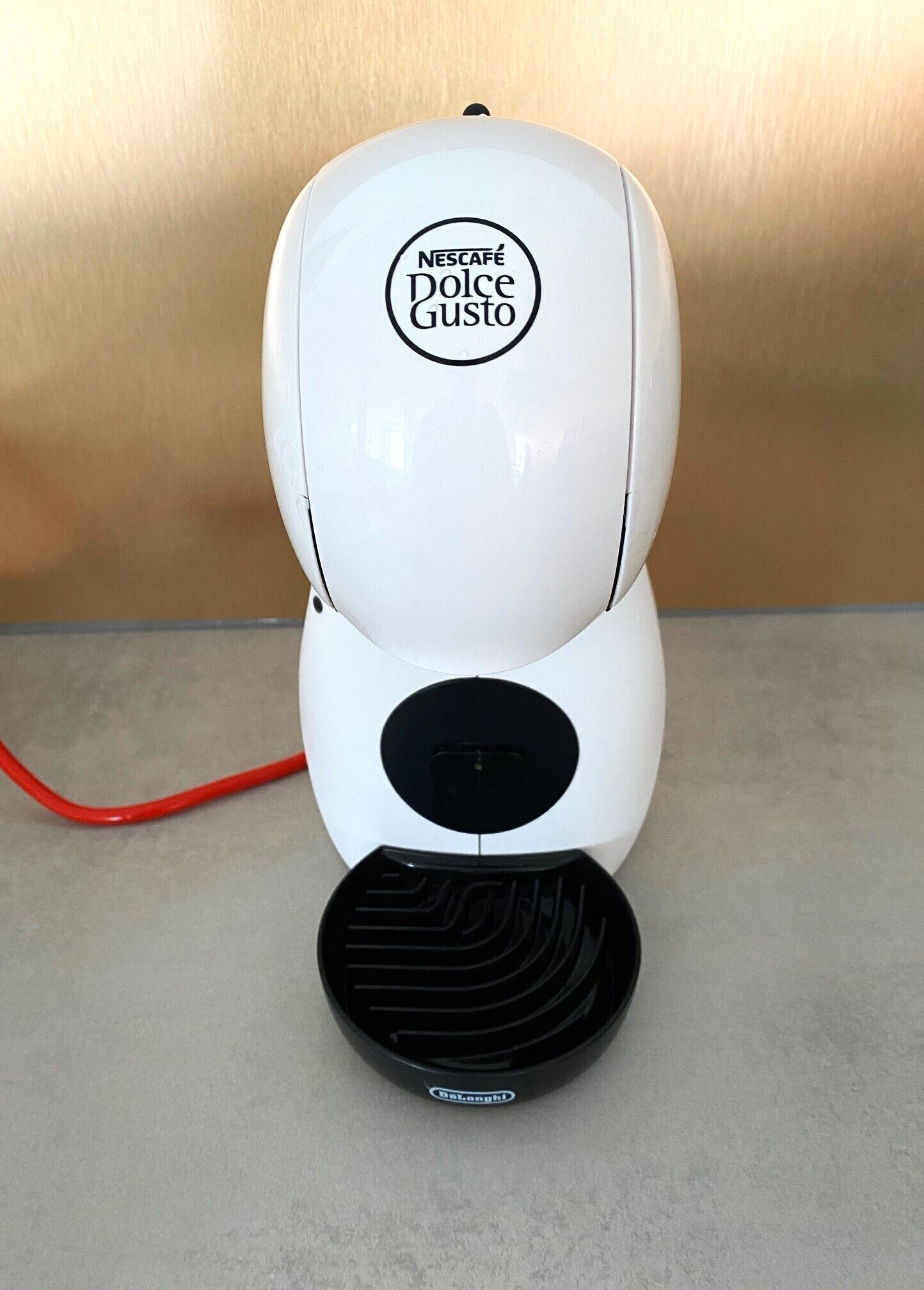 A white Nescafé Dolce Gusto coffee machine with a red cord.