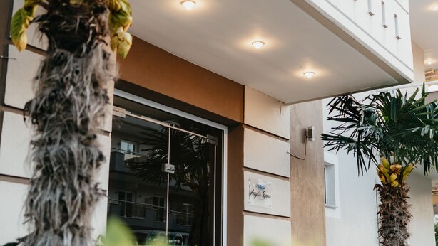 A modern building with a balcony, potted plants, and a sign that reads "Angelo Room". - Angela Rooms (Dio-Olympos)