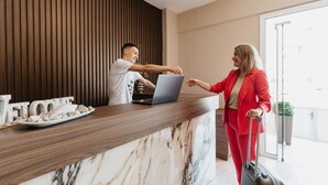 A reception desk with a laptop, a plate of cookies, and a 'WELCOME' sign. - Angela Rooms (Dio-Olympos)