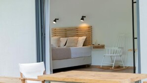 Quarto com cabeceira de madeira, cama com almofadas, mesa de cabeceira e cadeira de balanço.