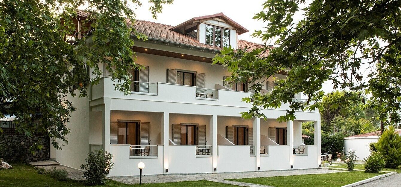 A two-story building with a white facade, multiple balconies, and a tiled roof.