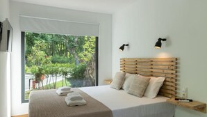 Quarto moderno com uma janela ampla, cabeceira de madeira e duas luminárias de cabeceira.