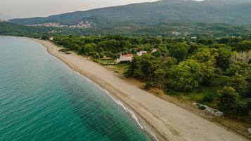 Enjoy a serene beachside retreat surrounded by lush green hills and dense vegetation.