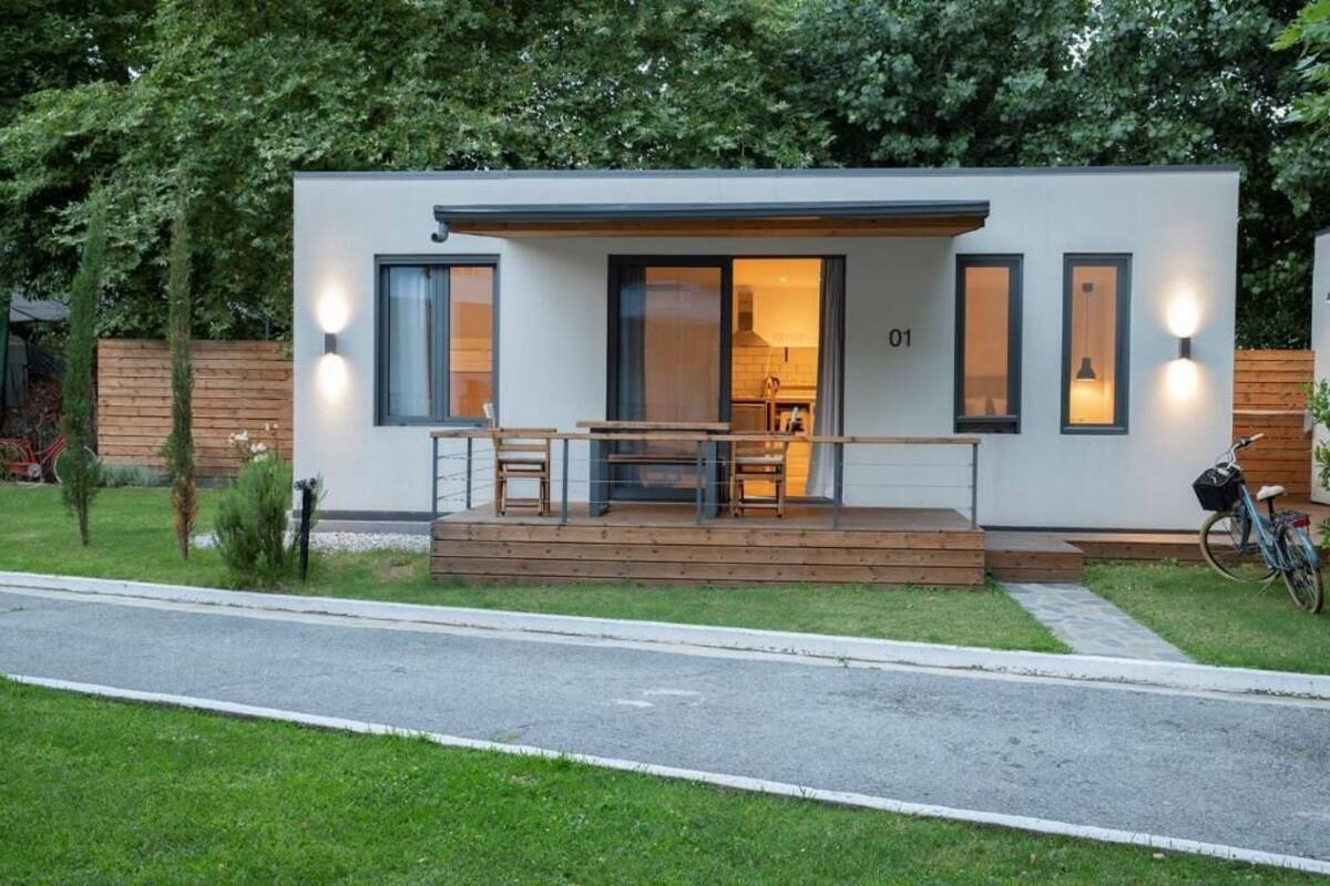 Ein modernes, eingeschossiges Haus mit einer Holzterrasse, einem Fahrrad und einem gepflegten Rasen.
