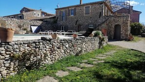 Un bâtiment en pierre doté d’un mur en pierre et d’un espace pavé aménagé avec des sièges pour l’extérieur.
