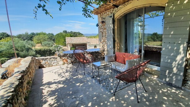 Un bâtiment en pierre doté d’un patio comprenant une table, des chaises et un canapé.