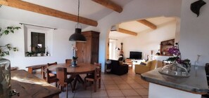 A spacious living area with a wooden dining table, a TV, and a kitchen counter. - Country house (sleeps 8, 10) in a quiet location, with a superb view of the Luberon. (Roussillon)
