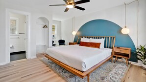 A bedroom with a bed, wooden nightstands, a ceiling fan, and a large rug. - The Starlite Inn (Carolina Beach)