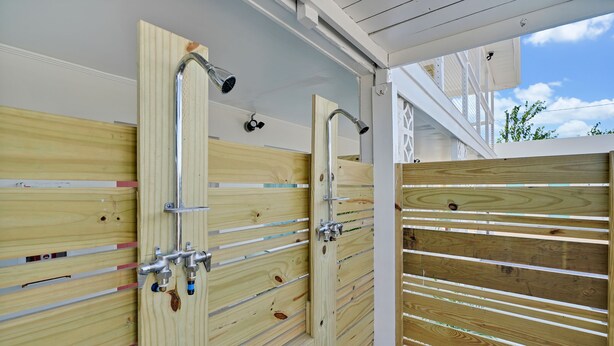 A wooden gate with a metal handle and a metal pipe, likely for a shower or water feature. - The Starlite Inn (Carolina Beach)