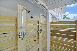 A wooden gate with a metal handle and a metal pipe, likely for a shower or water feature. - The Starlite Inn (Carolina Beach)