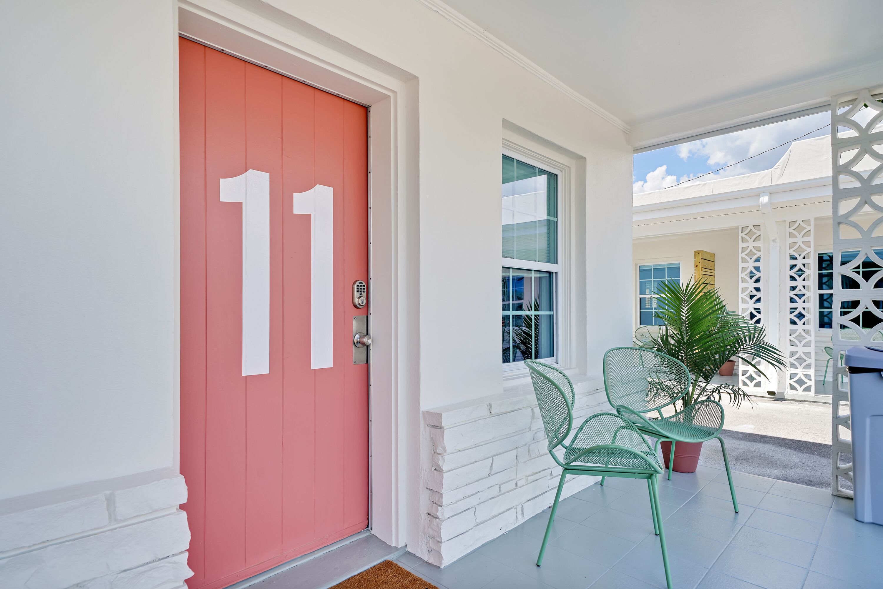 A red door with the number 11, a white door, and a window with a view of a building.
