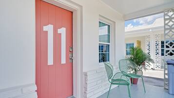 A red door with the number 11, a white door, and a window with a view of a building.