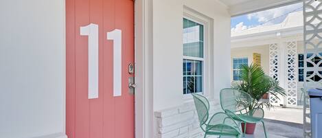 A red door with the number 11, a white door, and a window with a view of a building.