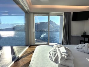 Ein Hotelzimmer mit großem Fenster und Blick auf einen See und Berge.