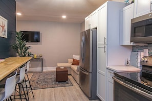 Cocina compacta con refrigerador, horno, microondas y un comedor con mesa y sillas.