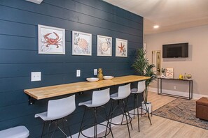 A modern kitchen with a wooden bar, white chairs, and framed artwork on the wall. - Beach Vibe 2 Miles to Whiskey Row Main Street Louisville Bourbon City Museum Row (Clarksville)