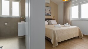 Habitación de hotel con cama, ventana, un cuadro y baño con inodoro y lavabo.