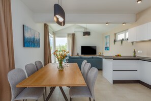 Eine moderne Küche mit Essbereich, einem Fernseher und einem großen Fenster.
