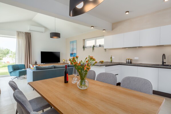 A modern living space with a dining area, kitchen, and a TV in the living room.