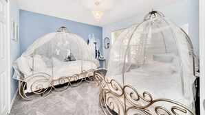 Ein Schlafzimmer mit zwei Betten, beide mit Baldachin. Der Raum hat eine blaue Wand, eine Chandelier und ein Wandgemälde mit Schlossmotiven.