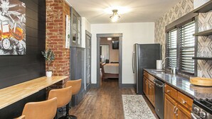 Una cocina con barra de madera, sillas, refrigerador y estufa.