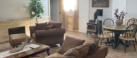Uma sala de estar com um sofá marrom, uma mesa de centro e um espaço de refeições com mesa e cadeiras.