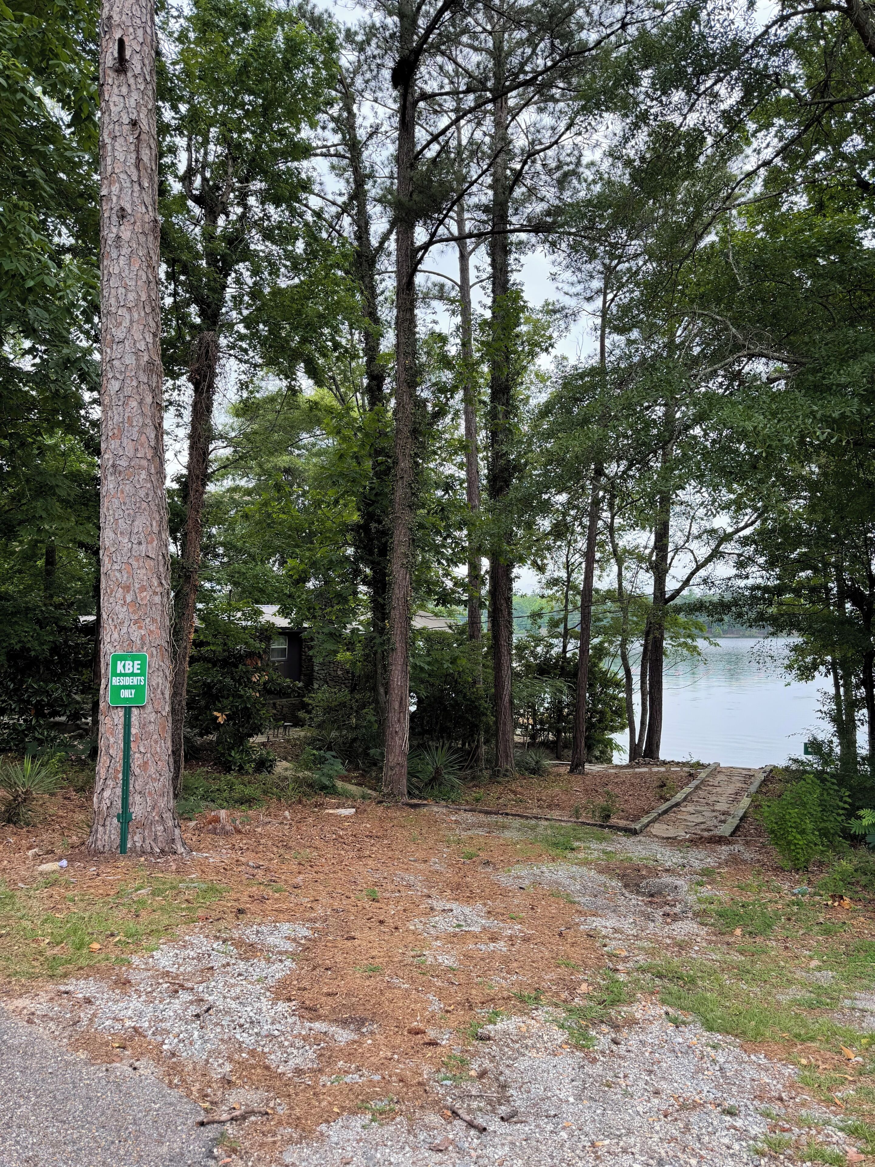 A natural setting with a sign indicating a private area for residents only, surrounded by trees and a body of water.