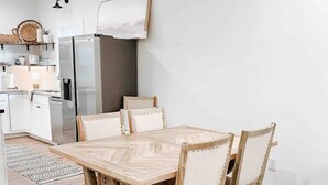 Uma cozinha moderna com armários brancos, forno embutido e geladeira.