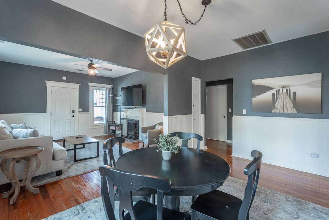 A modern living room with a fireplace, a dining area with a round table, and a large painting on the wall.