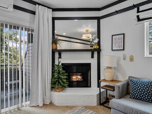 A living room with a fireplace, a staircase, a sofa, and a view of the outdoors.