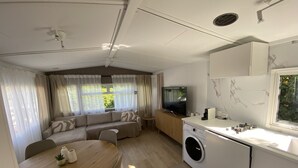 A compact living space with a sofa, TV, dining table, and washing machine.