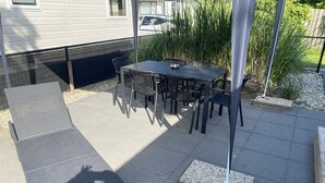 An outdoor patio with a table and chairs, a bench, and a metal pole.