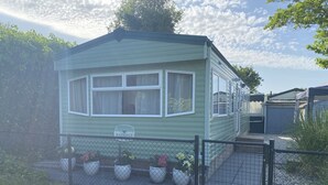 A mobile home with a fenced yard, a sign reading 'BAYSDALE,' and potted plants.