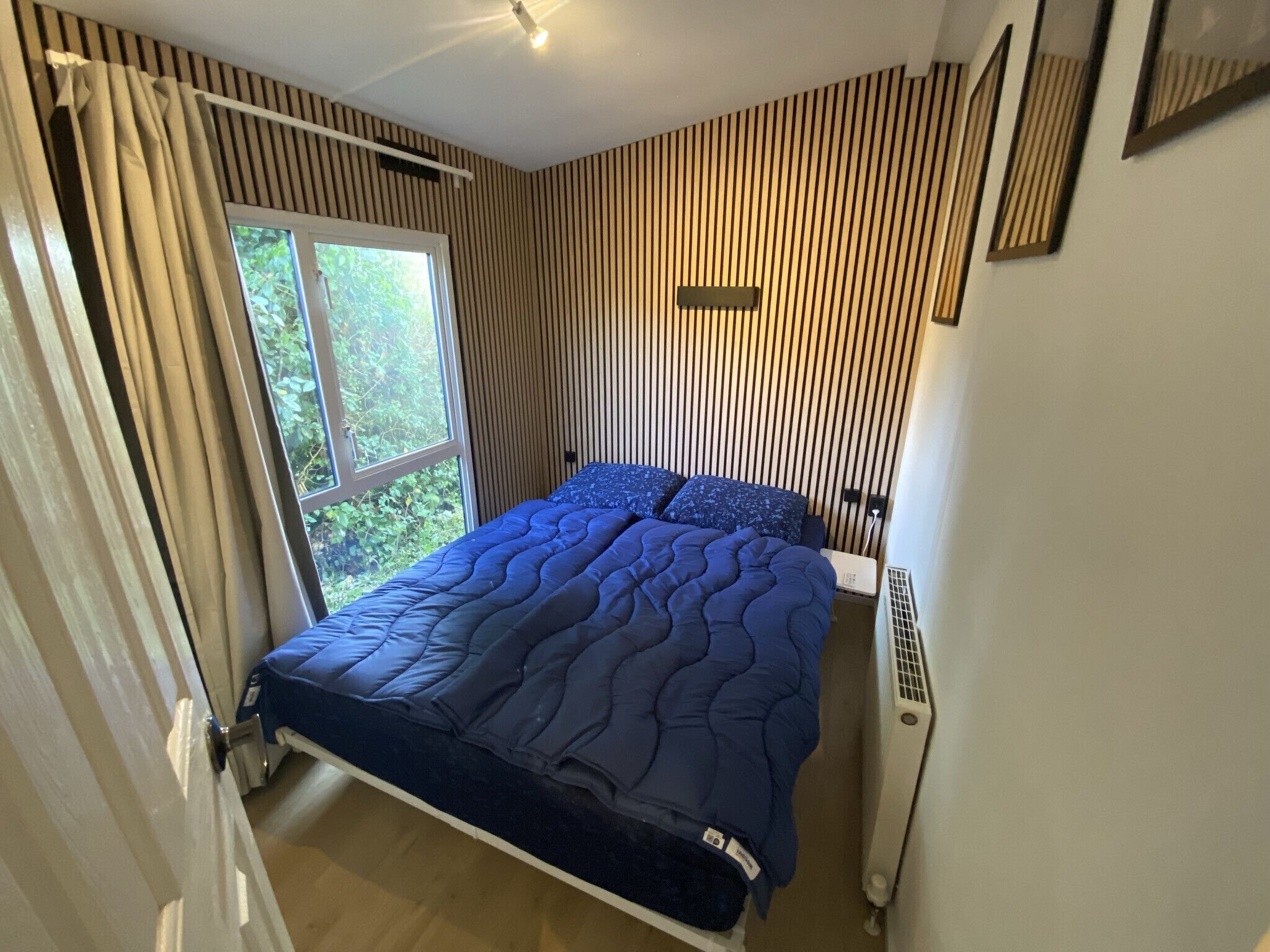 Een slaapkamer met een bed, een raam en een radiator.