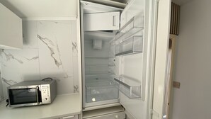 A compact kitchen with a microwave, oven, and a built-in refrigerator with multiple shelves.