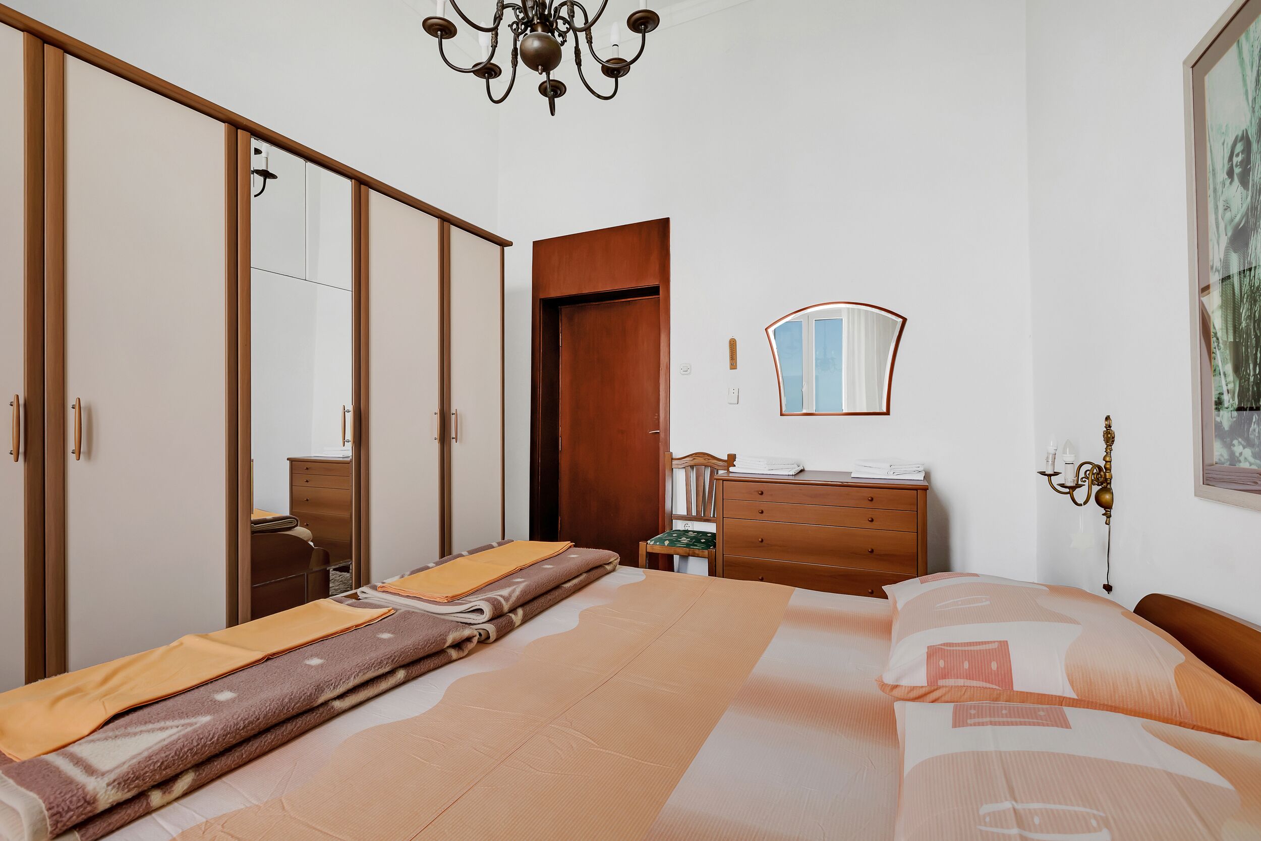 Un dormitorio con una cama, un aparador, un espejo y un armario.